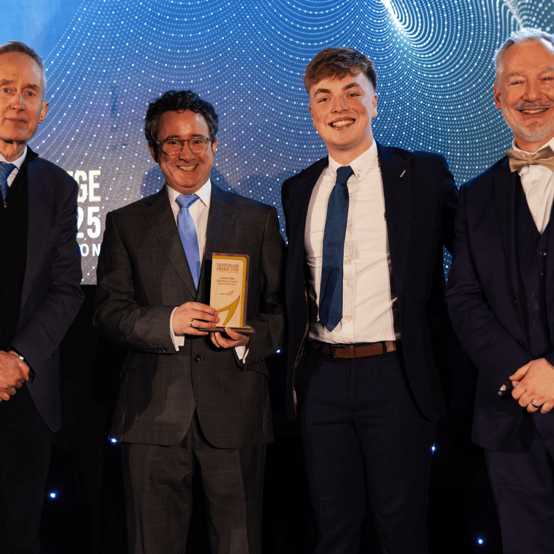 Four men in suits, one holding a trophy, stand smiling against a patterned blue backdrop.